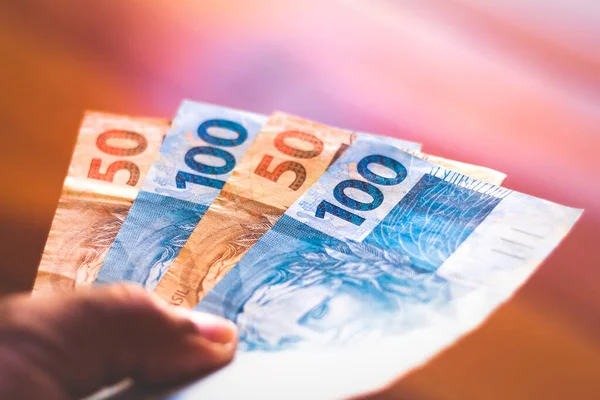 O homem detém cento e cinqüenta reais contas na mão. Brasil dinheiro e economia e conceito financeiro — Fotografia de Stock