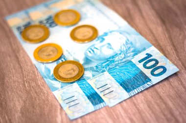 Bir gerçek para ve ahşap arka planda yüz tane gerçek banknot. Brezilya para ve maaş ve ekonomi kavramı