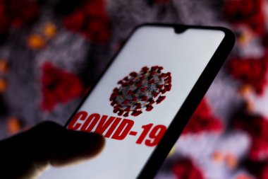 20 Mart 2020, Brezilya. Bu resimde Covid-19 virüsü akıllı telefon ekranında gösteriliyor. Arka planda Coronavirus görünüyor.