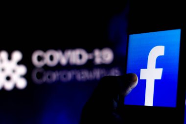 5 Nisan 2020, Brezilya. Bu resimde Facebook logosu, arka planda COVID-19 Coronavirus 'un bilgisayar modeli olan bir akıllı telefonda görüntülendi..