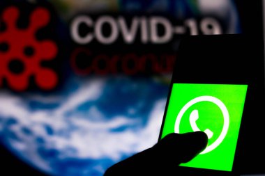 5 Nisan 2020, Brezilya. Bu resimde WhatsApp logosu, arka planda COVID-19 Coronavirus 'un bilgisayar modeli olan bir akıllı telefonda görüntülendi..