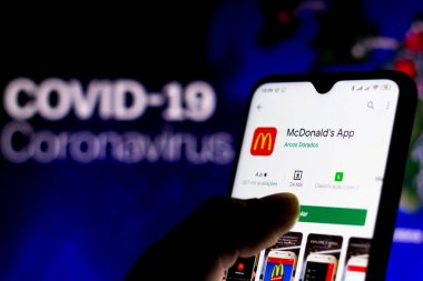 8 Nisan 2020, Brezilya. Bu resimde McDonalds logosu arka planda COVID-19 Coronavirus 'un bilgisayar modeli olan bir akıllı telefonda görüntülendi..