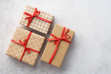 Kırmızı kurdeleyle süslenmiş kağıda sarılmış hediye kutuları.