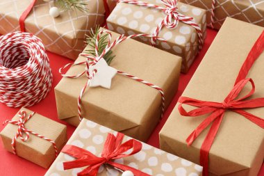 Kırmızı kurdele ve sicimle süslenmiş kağıda sarılmış hediye kutuları..