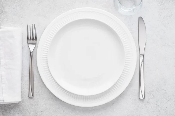 Table setting with white plates, glass, napkin, fork and knife. — Stock Photo, Image