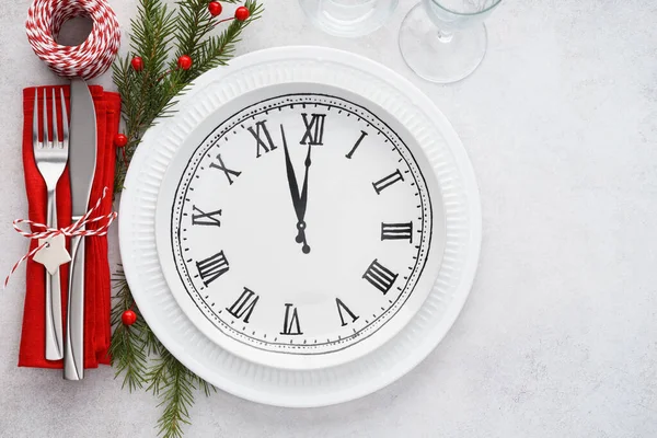 Christmas table setting with plate clock, napkin and cutlery.