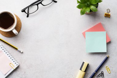 Bir fincan kahve, not defteri ve kırtasiye malzemesi olan bir işyeri.