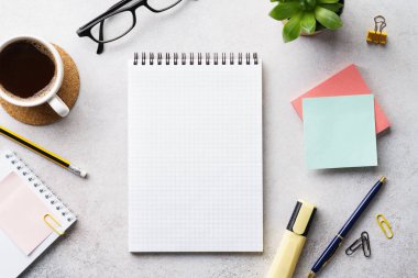 Boş bir defter, kırtasiye malzemesi ve bir fincan kahve..