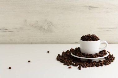 Beyaz bir fincan kahve çekirdekleri ile doludur.