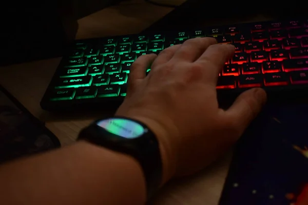 Hand with a clock on the keyboard in front of the monitor.