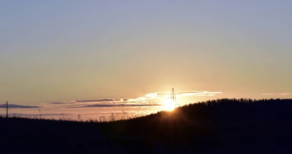 Dawn sun on the horizon of the hill and power lines