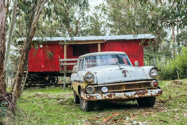 Ржавая старая машина припаркована перед старым железнодорожным вагоном — стоковое фото
