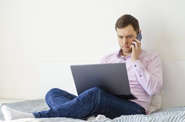 Coronavirus. Karantinaya alın. Gömlekli ve kotlu bir adam iş sorunlarını uzaktan çözer. Laptop ve telefon. Dünyada koronavirüs salgını.