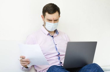 Coronavirus. Karantinaya alın. Gömlekli ve kotlu bir adam iş sorunlarını uzaktan çözer. Maskeli olan. Belgeler. Laptop ve telefon. Dünyada koronavirüs salgını.