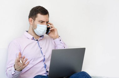 Coronavirus. Karantinaya alın. Gömlekli ve kotlu bir adam iş sorunlarını uzaktan çözer. Maskeli olan. Belgeler. Laptop ve telefon. Dünyada koronavirüs salgını.