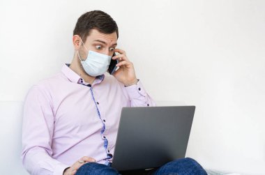 Coronavirus. Karantinaya alın. Gömlekli ve kotlu bir adam iş sorunlarını uzaktan çözer. Maskeli olan. Belgeler. Laptop ve telefon. Dünyada koronavirüs salgını.