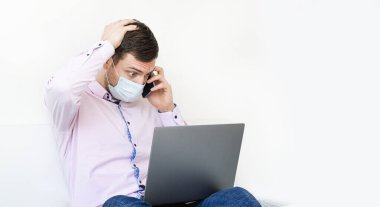 Coronavirus. Karantinaya alın. Gömlekli ve kotlu bir adam iş sorunlarını uzaktan çözer. Maskeli olan. Belgeler. Laptop ve telefon. Dünyada koronavirüs salgını.