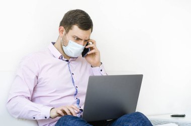 Coronavirus. Karantinaya alın. Gömlekli ve kotlu bir adam iş sorunlarını uzaktan çözer. Maskeli olan. Belgeler. Laptop ve telefon. Dünyada koronavirüs salgını.