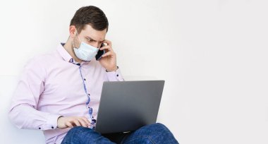 Coronavirus. Karantinaya alın. Gömlekli ve kotlu bir adam iş sorunlarını uzaktan çözer. Maskeli olan. Belgeler. Laptop ve telefon. Dünyada koronavirüs salgını.