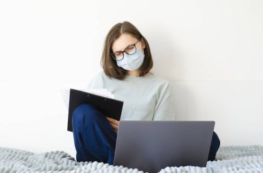 Coronavirus. Karantinaya alın. Gözlüklü ve maskeli bir kız. Uzaklık öğrenimi.