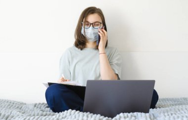 Coronavirus. Karantinaya alın. Gözlüklü ve maskeli bir kız. İş sorunlarını çözer, belgeleri imzalar.