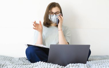 Coronavirus. Karantinaya alın. Gözlüklü ve maskeli bir kız. İş sorunlarını çözer, belgeleri imzalar.