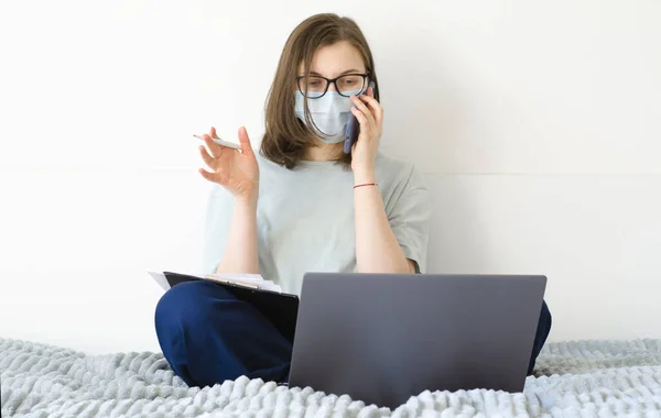 Coronavirus. Quarantaine. Een meisje met een bril en een masker. lost werkproblemen op, ondertekent documenten. — Stockfoto