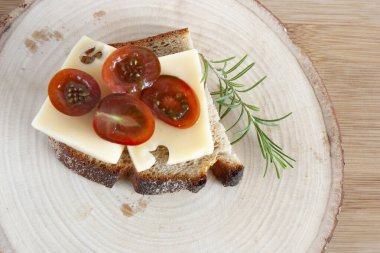 Tahtada peynir ve domatesli tam tahıllı sandviç.