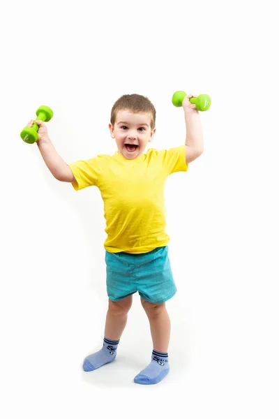 Küçük mutlu bir çocuk spor yapıyor, parlak yeşil dambılı olan bir spor.