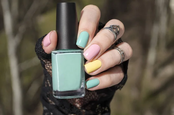 Spring colorful pastel manicure. Fresh Nature trendy nails. Woman hold nail polish bottle. Fashion Beauty hands. Stylish Nail polish. Salon professional manicure.