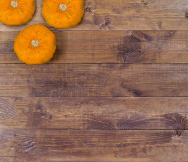 Kahverengi ahşap arka planda turuncu sonbahar balkabakları. Cadılar Bayramı konsepti, fotokopi alanı olan üst görünüm.