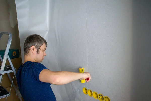 Home redecoration, young man glues wallpaper. Wallpapering in apartment. — Stock Image Home Redecoration Young Man Glues Wallpaper Wallpapering Apartment Royalty Free Stock Photos