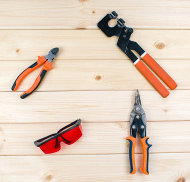 Tamir ve marangozluk için alet seti. Kırmızı koruyucu gözlük, düz burun pensesi ayarlanabilir anahtar, makas metali. Ahşap arka planda marangoz aletlerinin üst görüntüsü. İnşaat endüstrisi, diy. 