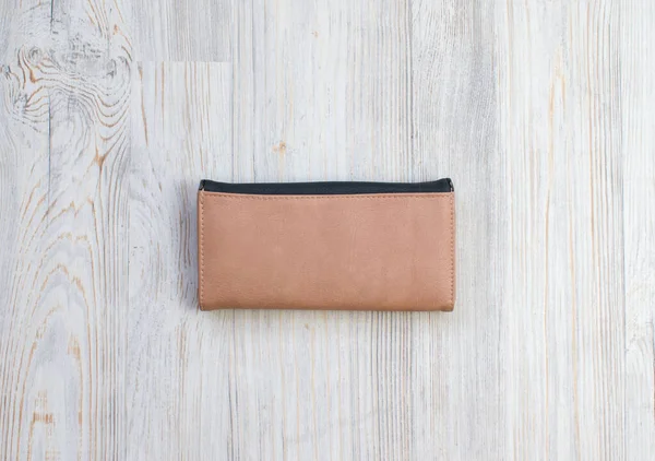 Woman wallet of natural leather isolated on wood background. Female purse black and beige color on a magnet.