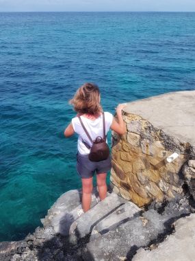 Kaya, taş ve Karayip Denizi bakar üzerinde kız duruyor