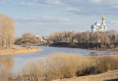 Nehir ve kilise manzaralı bir manzara. Bahar, ama henüz ağaçlarda yaprak yok.
