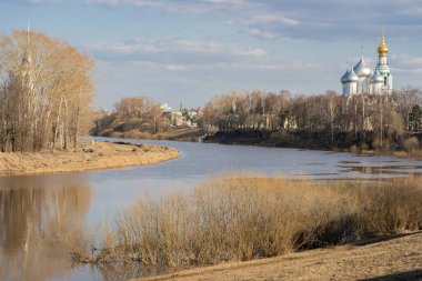 Nehir ve kilise manzaralı bir manzara. Bahar, ama henüz ağaçlarda yaprak yok.