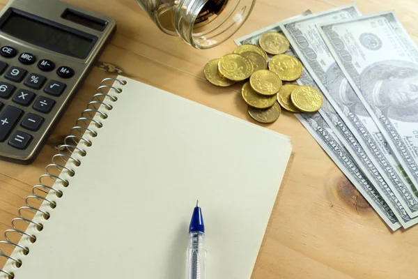 Conceptual image of notepad, money and calculator on wooden table. Selective focus.