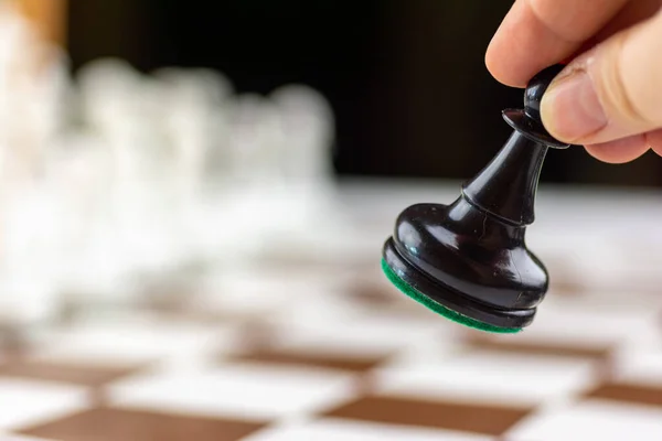 Kahverengi ve beyaz satranç tahtasında satranç saati olan siyah ve beyaz plastik satranç taşları.