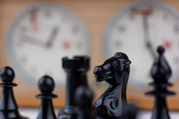 Relógio de xadrez antigo no tabuleiro de xadrez com figuras, bandeira em  posição que indica que o tempo está acabando em fundo escuro