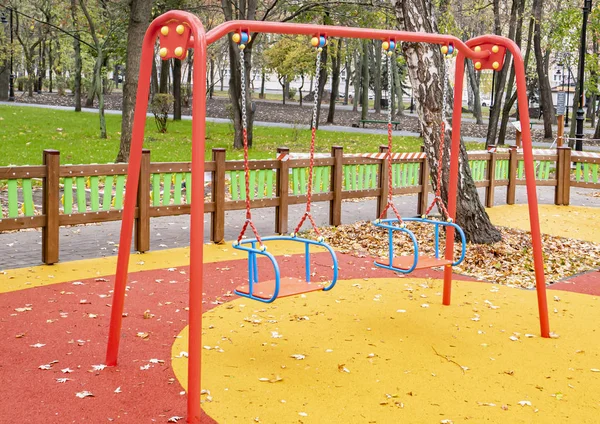 Parque infantil com um balanço no parque de outono . — Fotografia de Stock