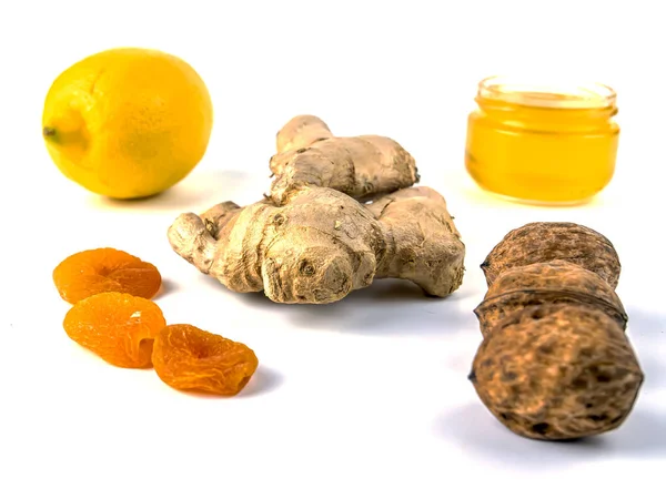 Med, kořen zázvoru, citron a vlašské ořechy na bílém pozadí. — Stock fotografie
