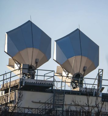 Mavi gökyüzüne karşı binanın çatısındaki uydu anteni..