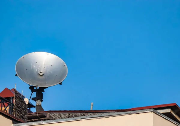 Antena parabólica no telhado do edifício contra o céu azul . — Fotografia de Stock