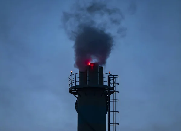 La cheminée fumante d'une entreprise la nuit . — Photo