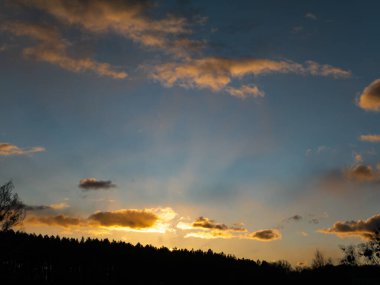 Orman ufkunun üzerindeki bulutlarda gün batımı.