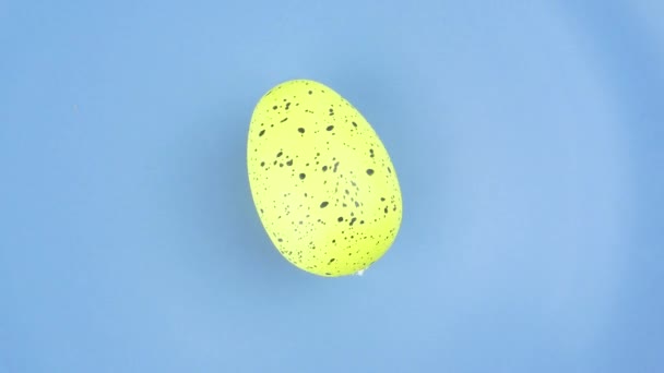 Um ovo de Páscoa colorido gira em um prato . — Vídeo de Stock