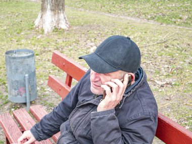 Beyzbol şapkalı bir adam cep telefonuyla konuşuyor. - İnsanlar. Mobil teknoloji. Ara bağlantı. İletişim. Reklamcılık.