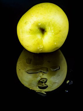 Siyah cam zemin üzerinde yansıması olan meyve yeşili elma damlaları. Arkaplan resmi. Yemek fotoğrafı. Mesaj için yer. Elmalar altın. Elma suyu.