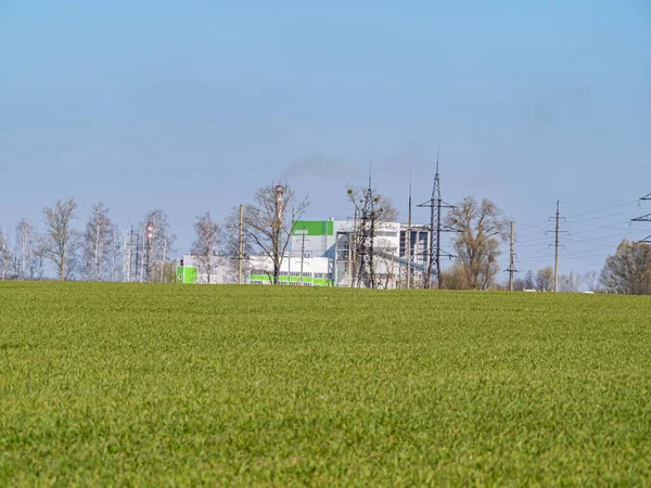 Industrial plant on a green field horizon of a farm. Cloud horizon. Agriculture. Place for text. Background image.